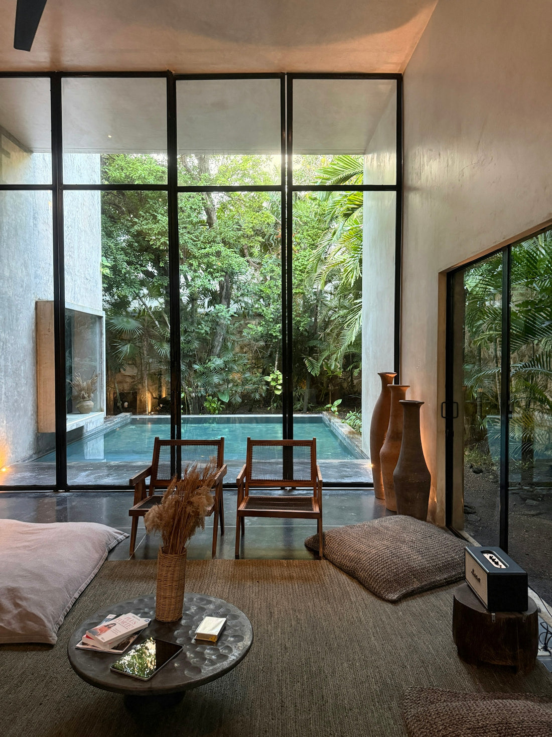 Modern living room with pool view and lush greenery.
